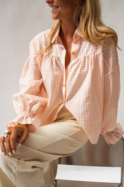 Chemise fluide à poignets élastiques portée par une femme, assise, poignets bouffants, chaise grise
