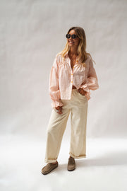 Chemise fluide à poignets élastiques portée par une femme, vue de face, lunettes de soleil, pantalon écru