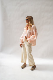 Chemise fluide à poignets élastiques portée par une femme, vue de face, fond blanc, pantalon écru