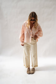 Chemise fluide à poignets élastiques portée par une femme, vue de face, fond blanc, mules marron