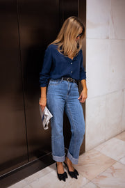 Chemise fluide en coton portée par une femme, silhouette entière, porte noire, pochette, jean