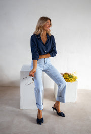 Chemise fluide en coton portée par une femme, silhouette entière, cube blanc, jean clair, escarpins