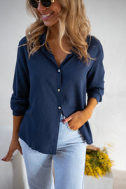 Chemise fluide en coton portée par une femme, vue rapprochée, manches retroussées, jean