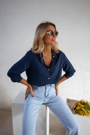 Chemise fluide en coton portée par une femme, vue rapprochée, mains sur les hanches, lunettes de soleil