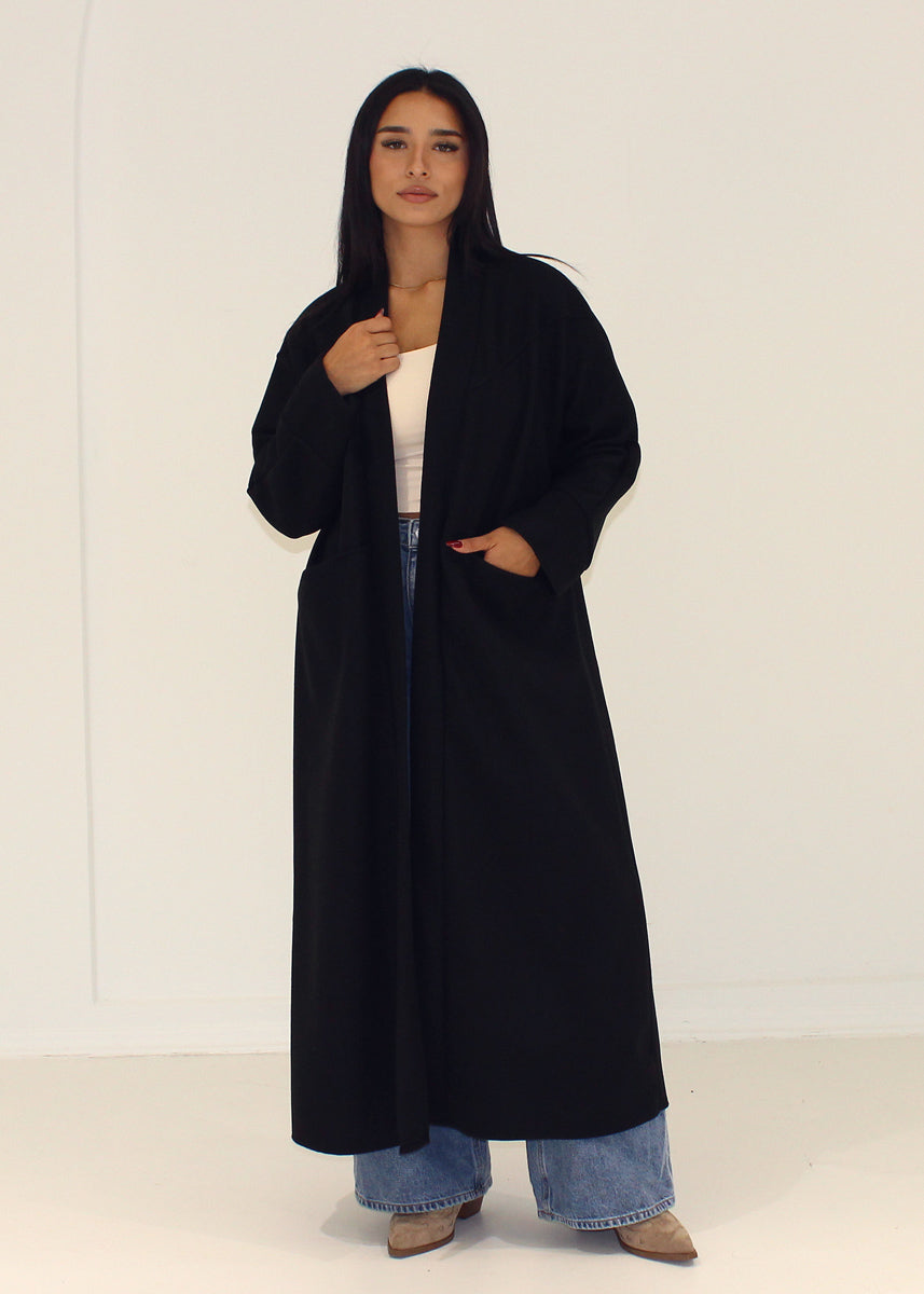 Manteau noir ample à poches — vue portée en pied.