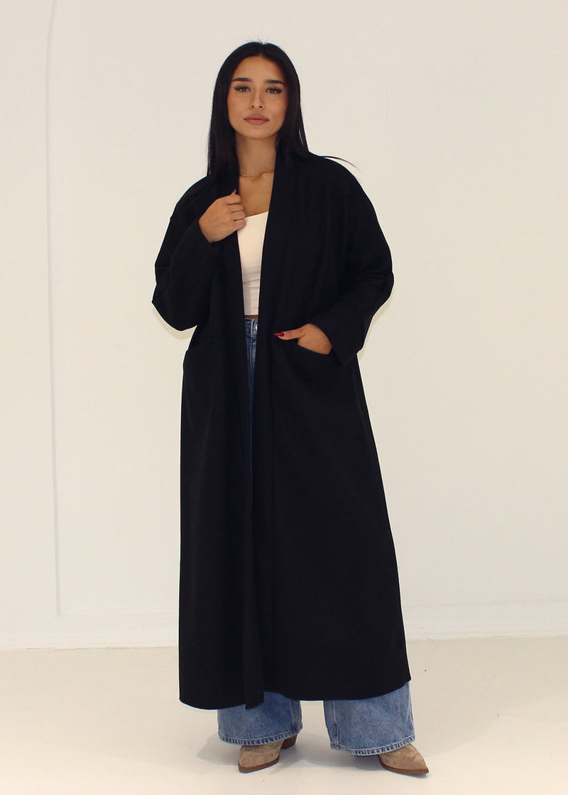 Manteau noir ample à poches — vue portée en pied.