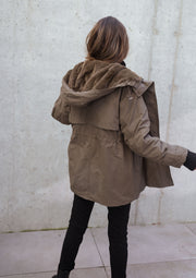 Manteau imperméable à capuche fourrée porté par une femme, vue de dos, capuche relevée