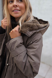 Manteau imperméable à capuche fourrée porté par une femme, vue rapprochée, capuche fourrée, sourire