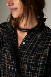 Blouse noire à carreaux fins — gros plan du col à volants
