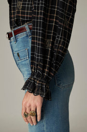 Blouse noire à carreaux fins — détail de la manche et du poignet