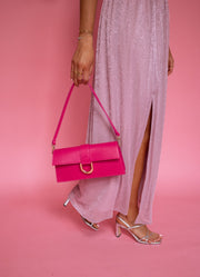 Robe longue à lurex brillant portée par une femme, vue rapprochée, fente, pochette fuchsia