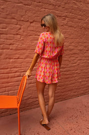 Combishort fluide ouverture buste porté par une femme, vue de dos, chaise orange, cheveux blonds