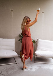 Robe fluide effet soie fendue portée par une femme, vue de trois-quarts, verre, bras levé