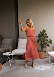 Robe fluide effet soie fendue portée par une femme, vue de face, table d'appoint, bras levé
