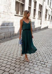 Robe fluide effet soie portée par une femme, vue de face, ruelle pavée, pochette bleue