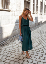 Robe fluide effet soie portée par une femme, vue de face, ruelle, main dans les cheveux