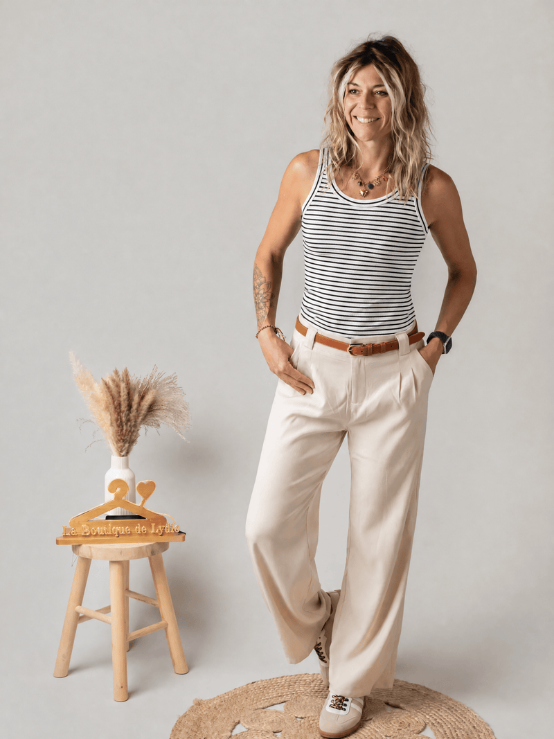 Débardeur rayé en maille côtelée porté par une femme, silhouette entière, pantalon beige, tabouret