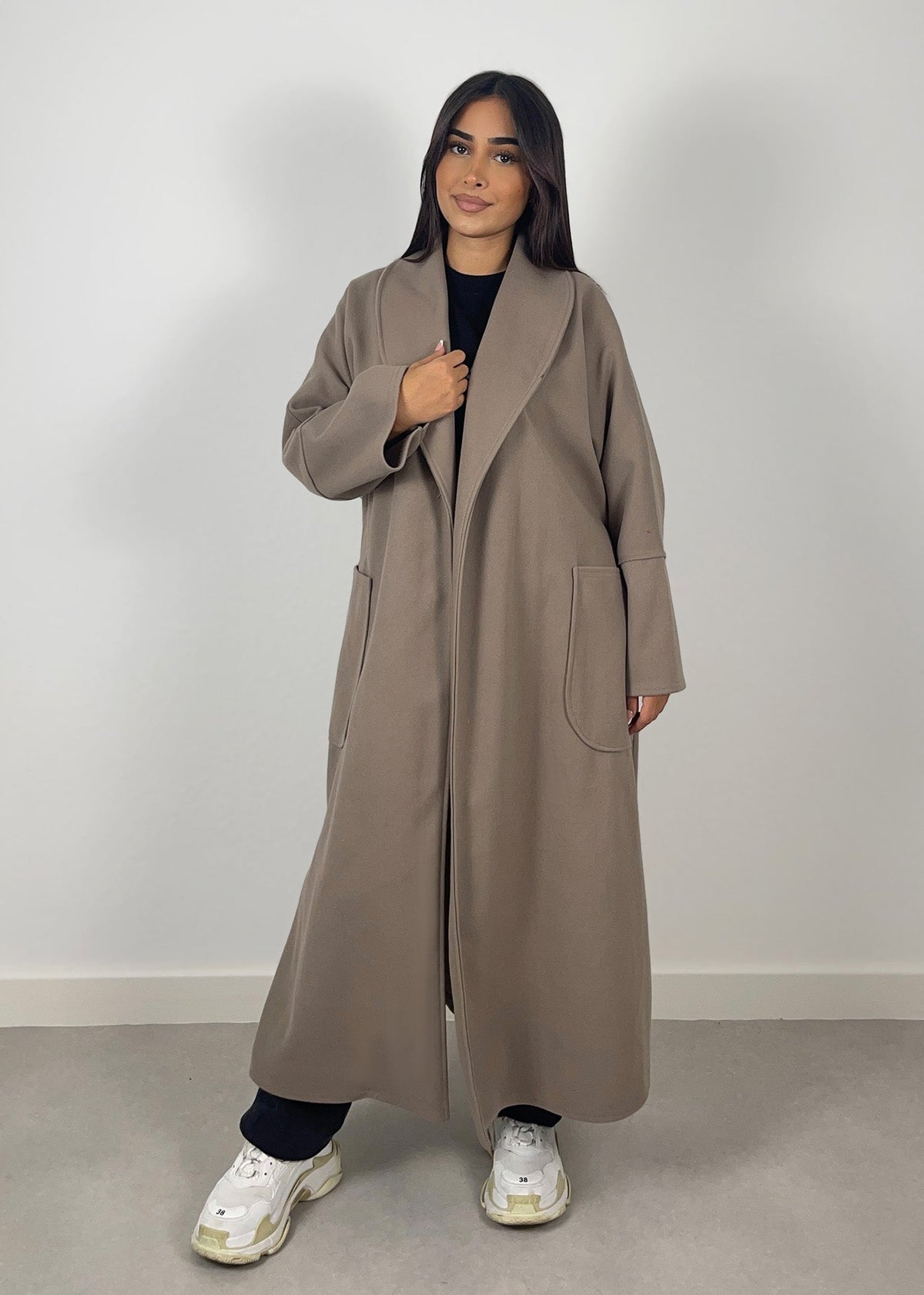 Manteau taupe à ceinture — vue portée en pied, ouvert sur un haut noir et pantalon blanc