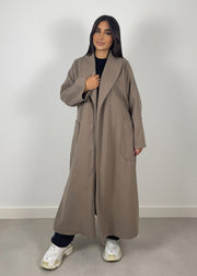 Manteau taupe à ceinture — vue portée en pied, ouvert sur un haut noir et pantalon blanc