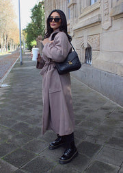 Manteau taupe à ceinture — vue portée en marche en extérieur, lunettes de soleil et sac noir