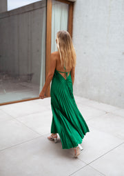 Robe plissée dos ouvert portée par une femme, vue de dos, patio, jupe plissée