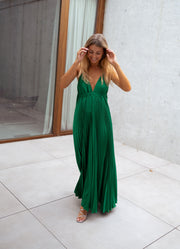 Robe plissée dos ouvert portée par une femme, vue de face, baie vitrée, bras levé