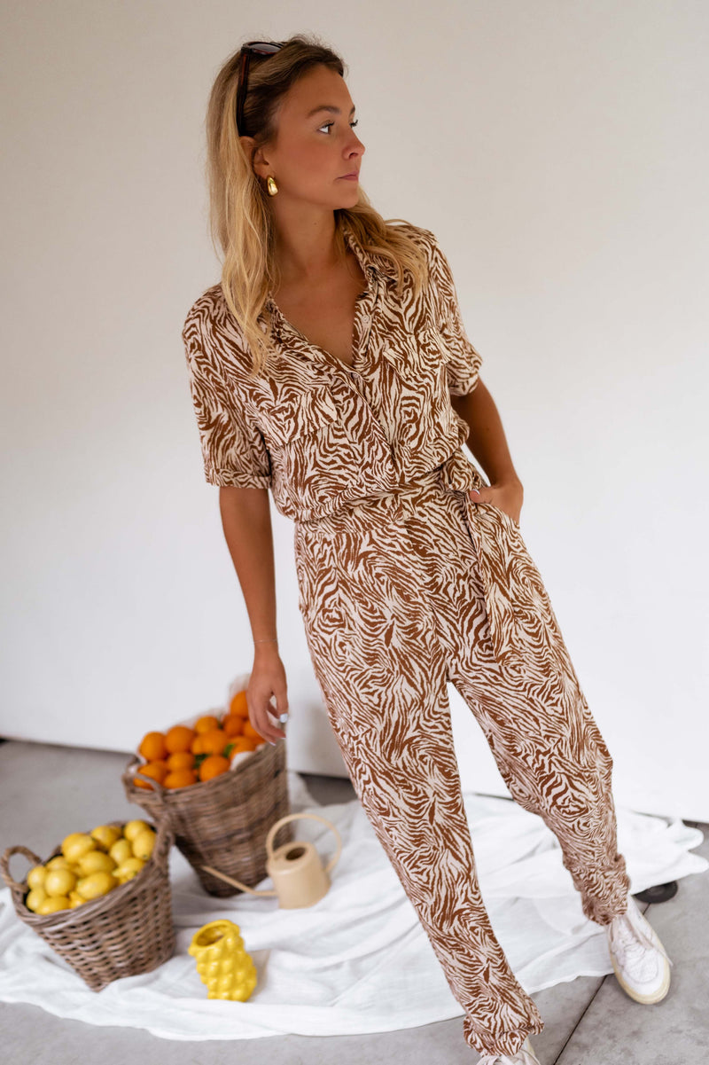 Combinaison zébrée à col chemise portée par une femme, vue de face, paniers d'oranges, baskets blanches