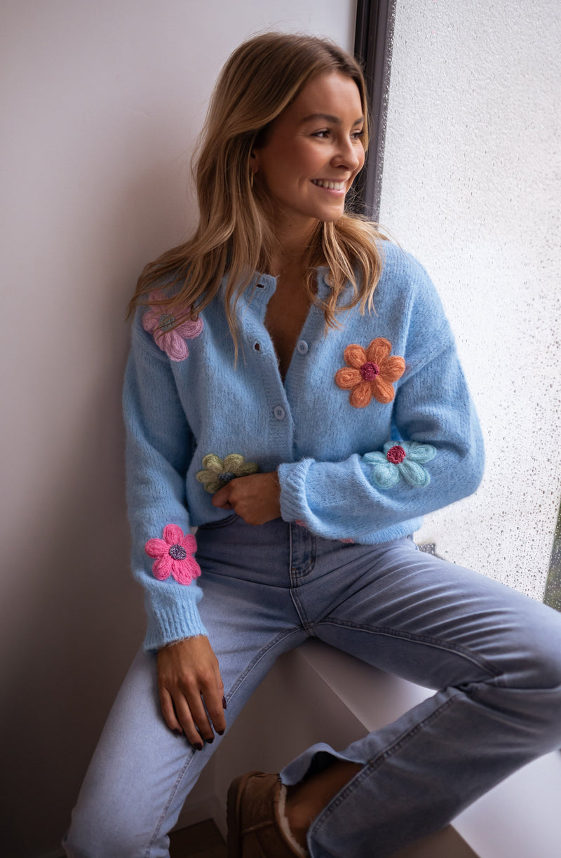 Gilet à fleurs brodées porté par une femme, assise, sur un rebord de fenêtre, fleurs brodées