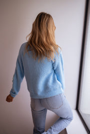 Gilet à fleurs brodées porté par une femme, vue de dos, cheveux longs, jean clair