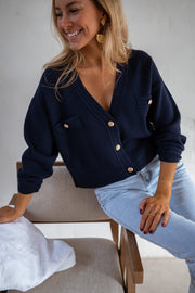 Gilet à boutons porté par une femme, assise, sur une chaise, jean clair