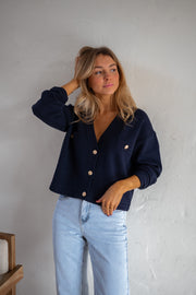 Gilet à boutons porté par une femme, vue rapprochée, main dans les cheveux