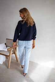 Gilet à boutons porté par une femme, vue de trois-quarts, cheveux longs, chaise