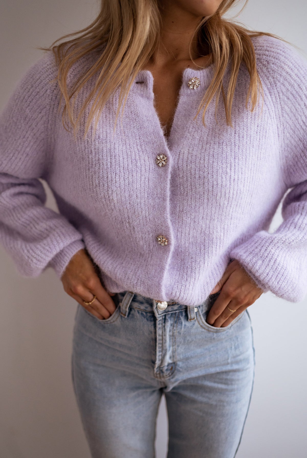 Gilet à boutons fleuris brillants porté par une femme, vue rapprochée, mains dans les poches, jean clair