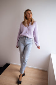 Gilet à boutons fleuris brillants porté par une femme, silhouette entière, jean clair, de loin