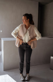 Gilet sans manches effet moumoute porté par une femme, silhouette entière, gilet beige, plan de travail