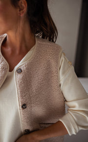 Gilet sans manches effet moumoute porté par une femme, vue rapprochée, de côté, gilet beige