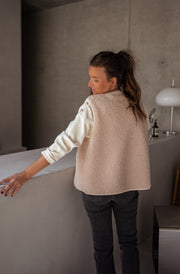 Gilet sans manches effet moumoute porté par une femme, vue de dos, gilet beige, queue de cheval