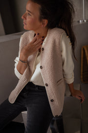 Gilet sans manches effet moumoute porté par une femme, vue de profil, regard de côté, gilet beige
