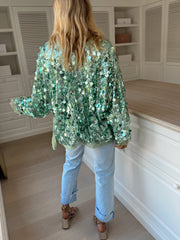 Gilet cache-cœur à paillettes porté par une femme, vue de trois-quarts, placard blanc, cheveux blonds