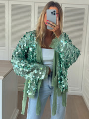 Gilet cache-cœur à paillettes porté par une femme, vue de face, selfie dans le miroir, jean clair