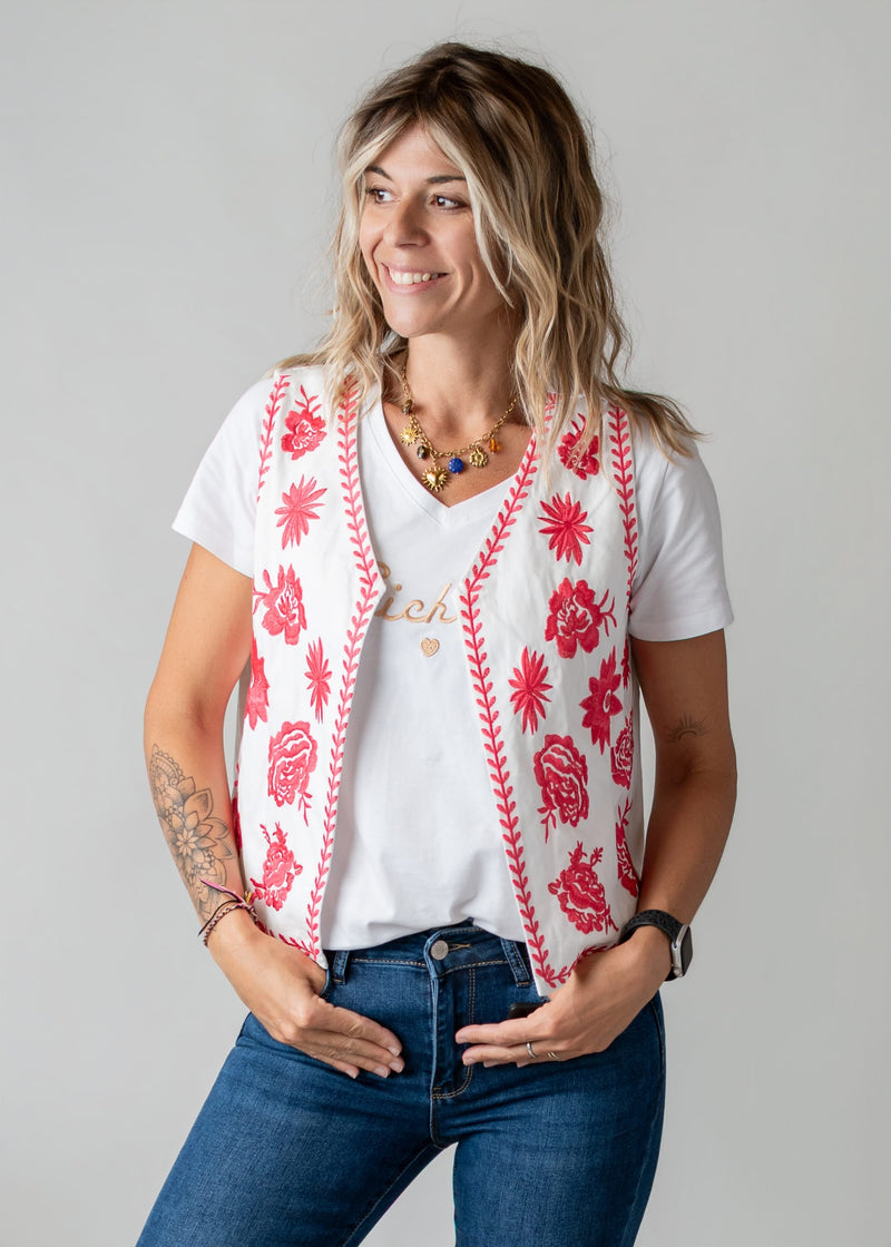 Gilet brodé floral sans manches porté par une femme, vue de trois-quarts, t-shirt blanc, jean flare