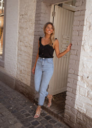 Top à volants boutonné porté par une femme, silhouette entière, pavés, porte