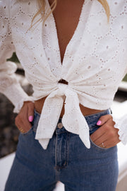 Blouse courte brodée manches longues portée par une femme, vue rapprochée, nœud, jean