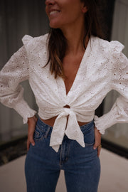 Blouse courte brodée manches longues portée par une femme, vue rapprochée, manches bouffantes, nœud