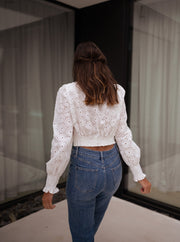 Blouse courte brodée manches longues portée par une femme, vue de dos, rideau, jean