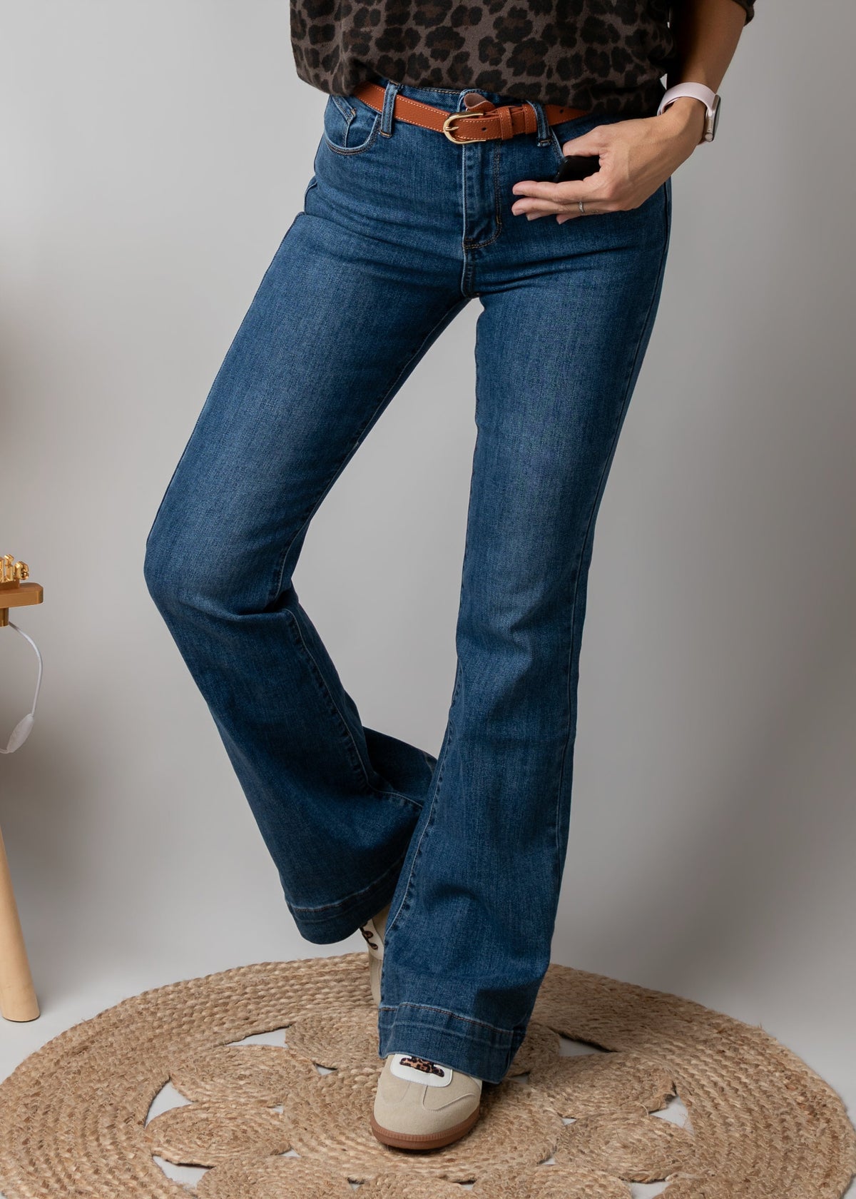 Jean flare en denim stretch porté par une femme, vue rapprochée, jean flare, ceinture marron