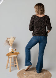 Jean flare en denim stretch porté par une femme, vue de dos, jean flare, haut noir