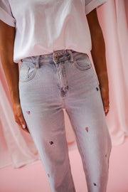 Jeans fleuri taille haute porté par une femme, vue rapprochée, petites fleurs brodées