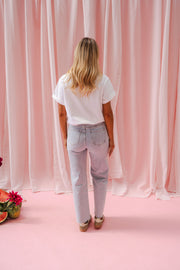 Jeans fleuri taille haute porté par une femme, vue de dos, rideaux roses