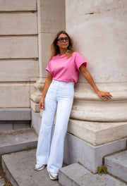 Jean évasé taille haute porté par une femme, vue de trois-quarts, colonne, t-shirt rose